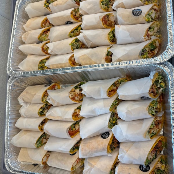 Two foil trays filled with individually wrapped burritos, some with 'Safely TamperSafe' stickers.